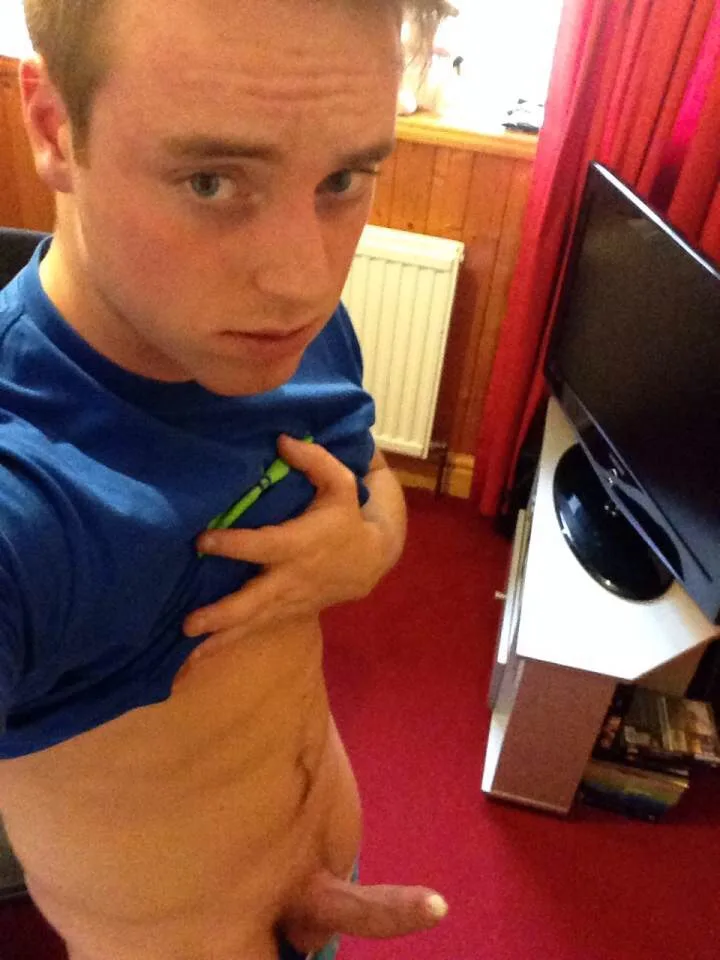 Amateur lad in blue tee lifts shirt to show hard cock peeking out at camera