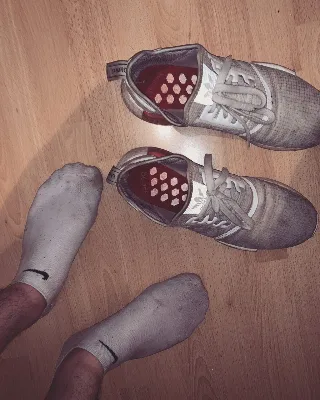 Guy in sweaty Nike socks beside dirty Adidas trainers on wood floor