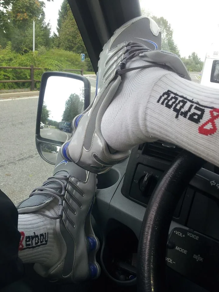 Garoto de tênis e meias relaxa no carro, pés no painel, clima casual de fetiche por pés