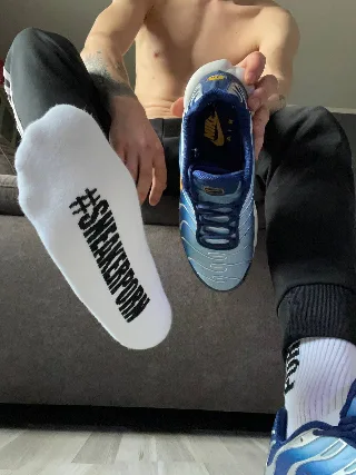 Shirtless guy flexing sneaker-clad feet with #SNEAKERPORN soles and blue Nikes in hand