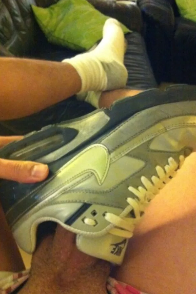 Cara de meias brancas e tênis Nike flexiona os pés no sofá, pernas bem abertas