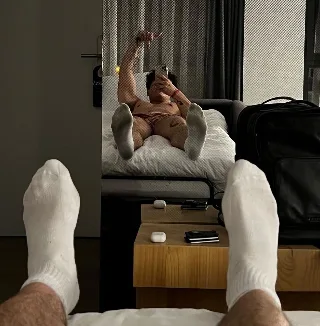 Sock-clad feet front and center as guy snaps mirror selfie in hotel room