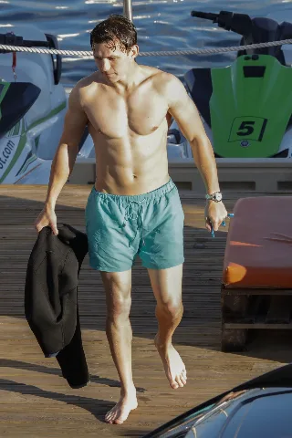 Tom Holland shirtless on dock, muscular abs and swim trunks after water fun