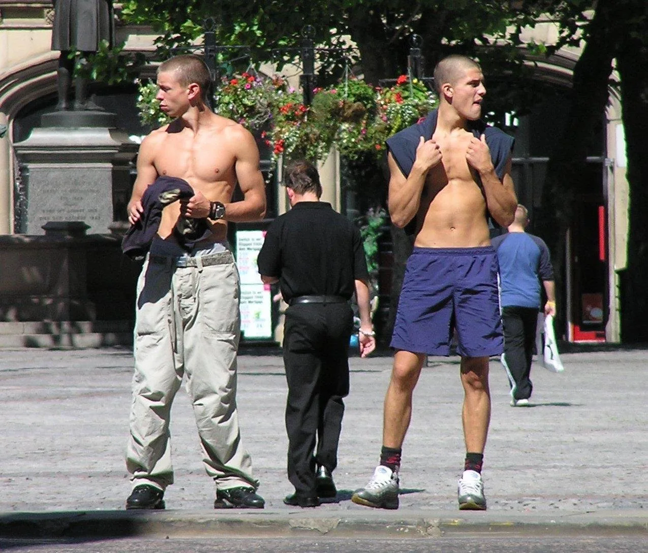 Skørtløse uhyggelige drenge i cargo bukser og shorts flash abs på solrige gade