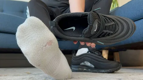 Guy in black joggers shows off worn socks and Nike Air Max 97s, foot fetish focus on soles and toes