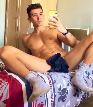 Hot young lad in socks takes mirror selfie with legs spread wide on bed