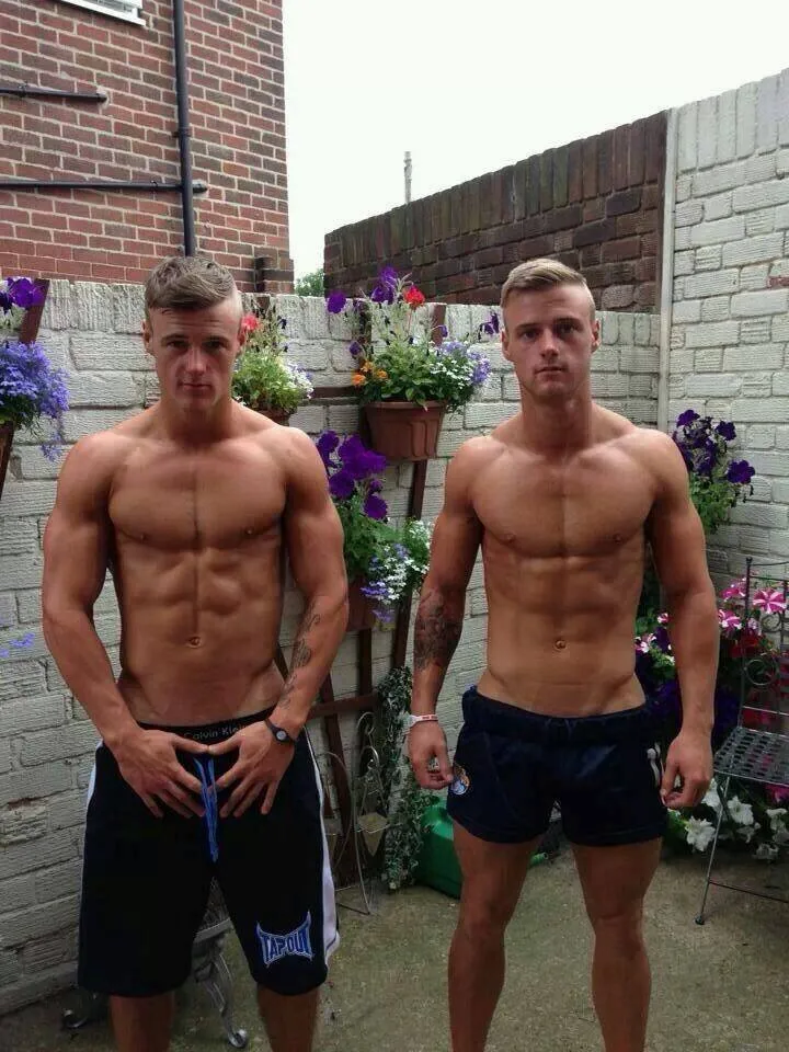 To rippede drenge i atletiske shorts flettende shorts i en have, uhyggelige vibes med synlige abs og tatoveringer